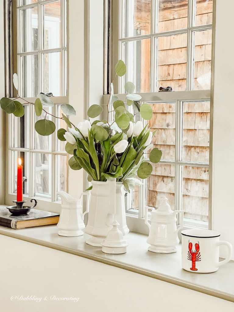 White and greenery flower bouquet on windowsill.