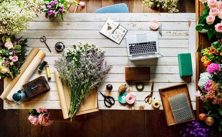 A vintage desk adorned with flowers and a laptop, perfect for home decorating.