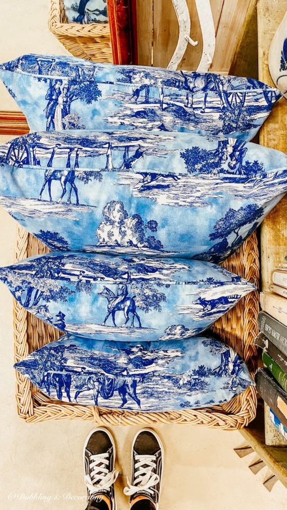 Four blue vintage style pillows in basket at Stone House Antique Center, Vermont.