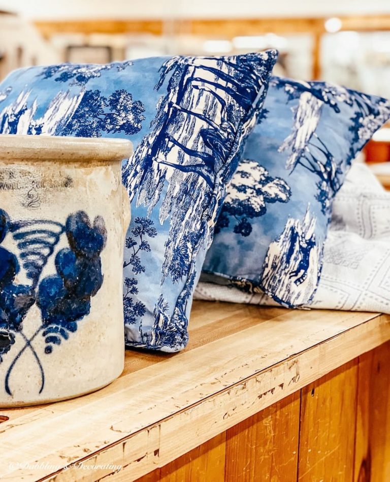 Vintage Porch crock with blue pillows on antique store check out counter.