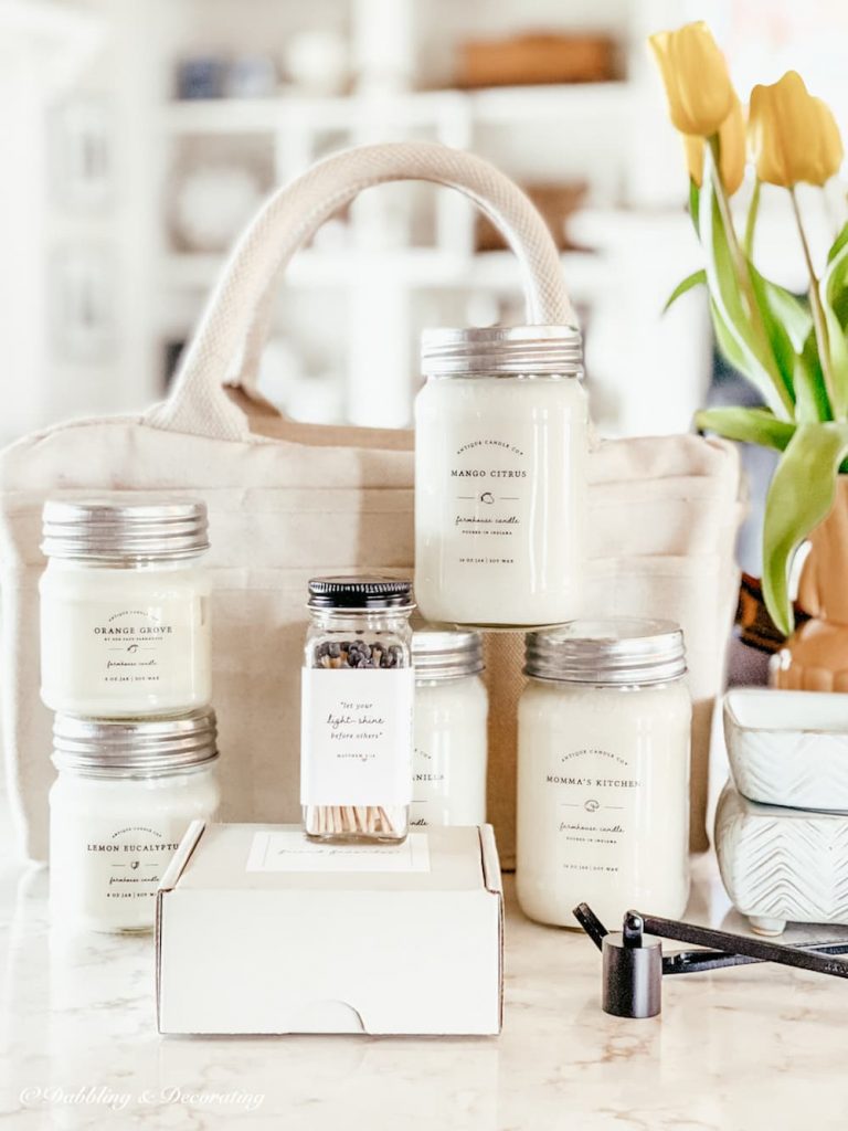 5 Mason jars of farmhouse candles stacked with matches, candle snuffer and white canvas storage bag.  How to Store Candles?