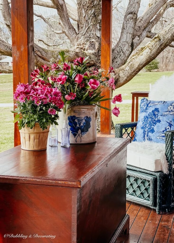 Antique trunk refinished with spring floral arrangements on spring porch.