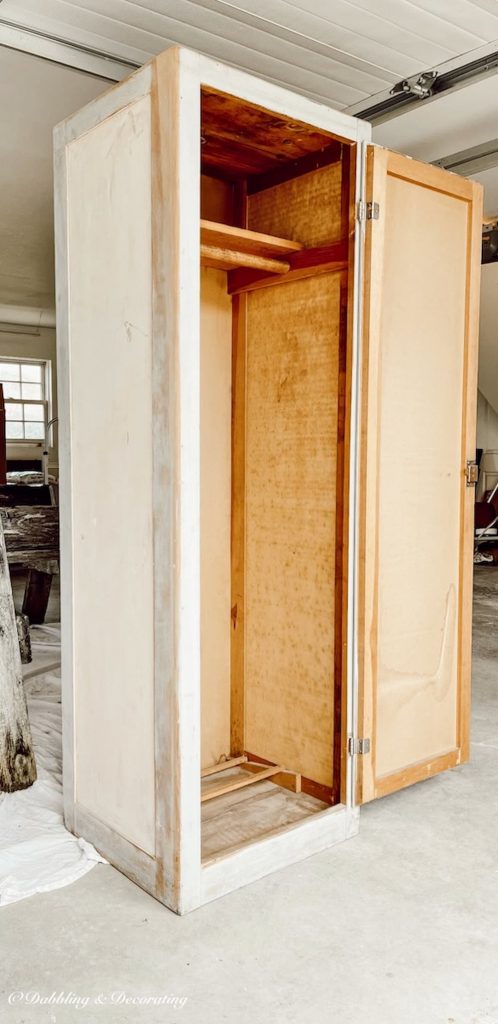 Wardrobe closet with doors freestanding with open door in garage before refinishing.