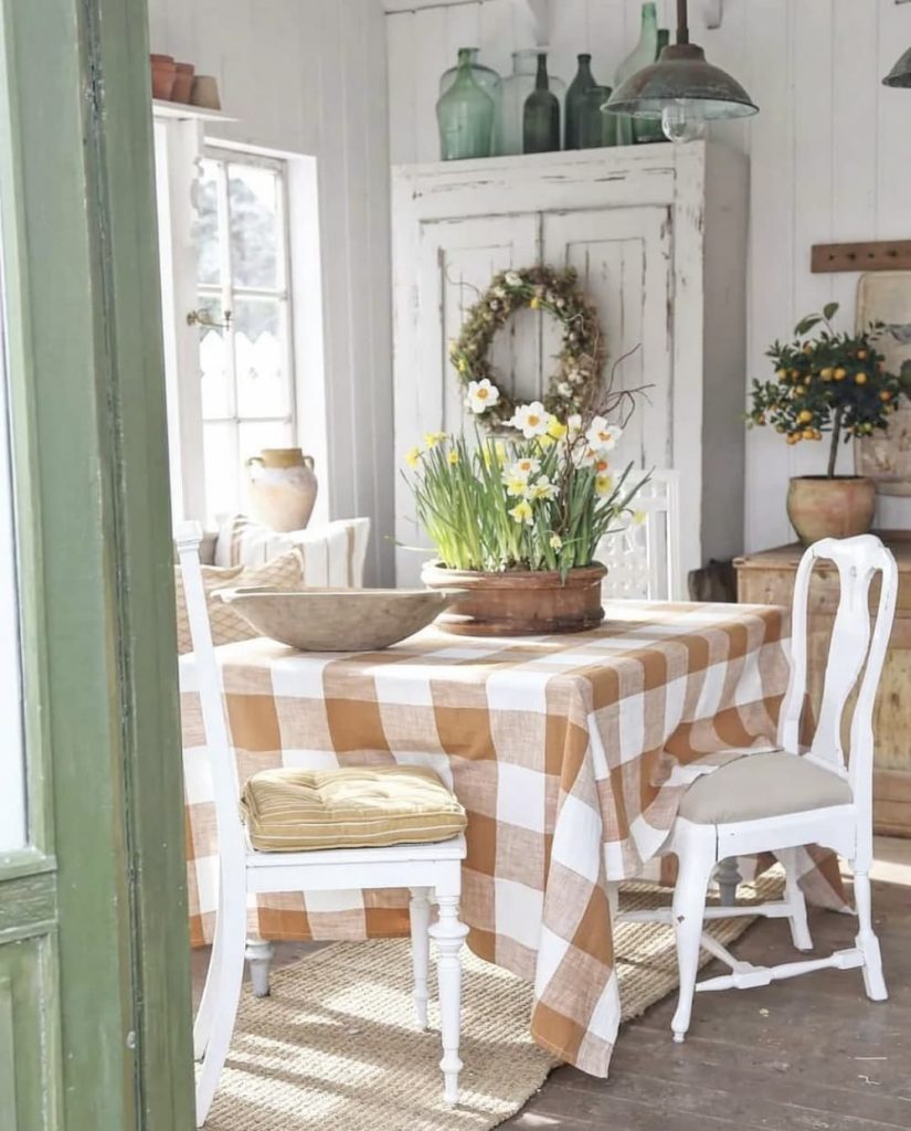 A vintage dining room with white chairs and a checkered tablecloth, exuding thrifty charm and stylish home decor.