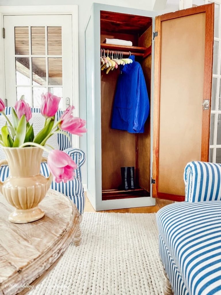 Freestanding closet wardrobe with coat and boots.