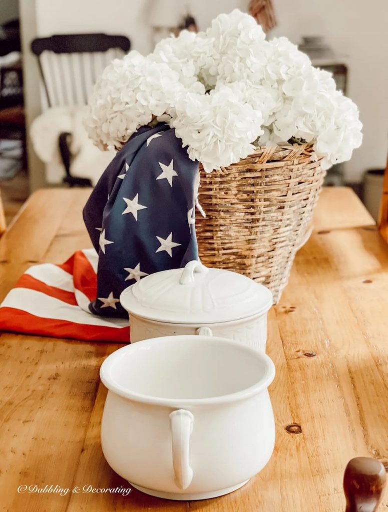 Vintage Patriotic Decor on table with basket, white hydrangeas and USA flag.