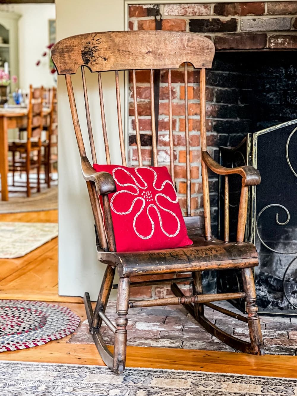 Antique Boston Rocker Chair in front of colonial fireplace with red pillow.