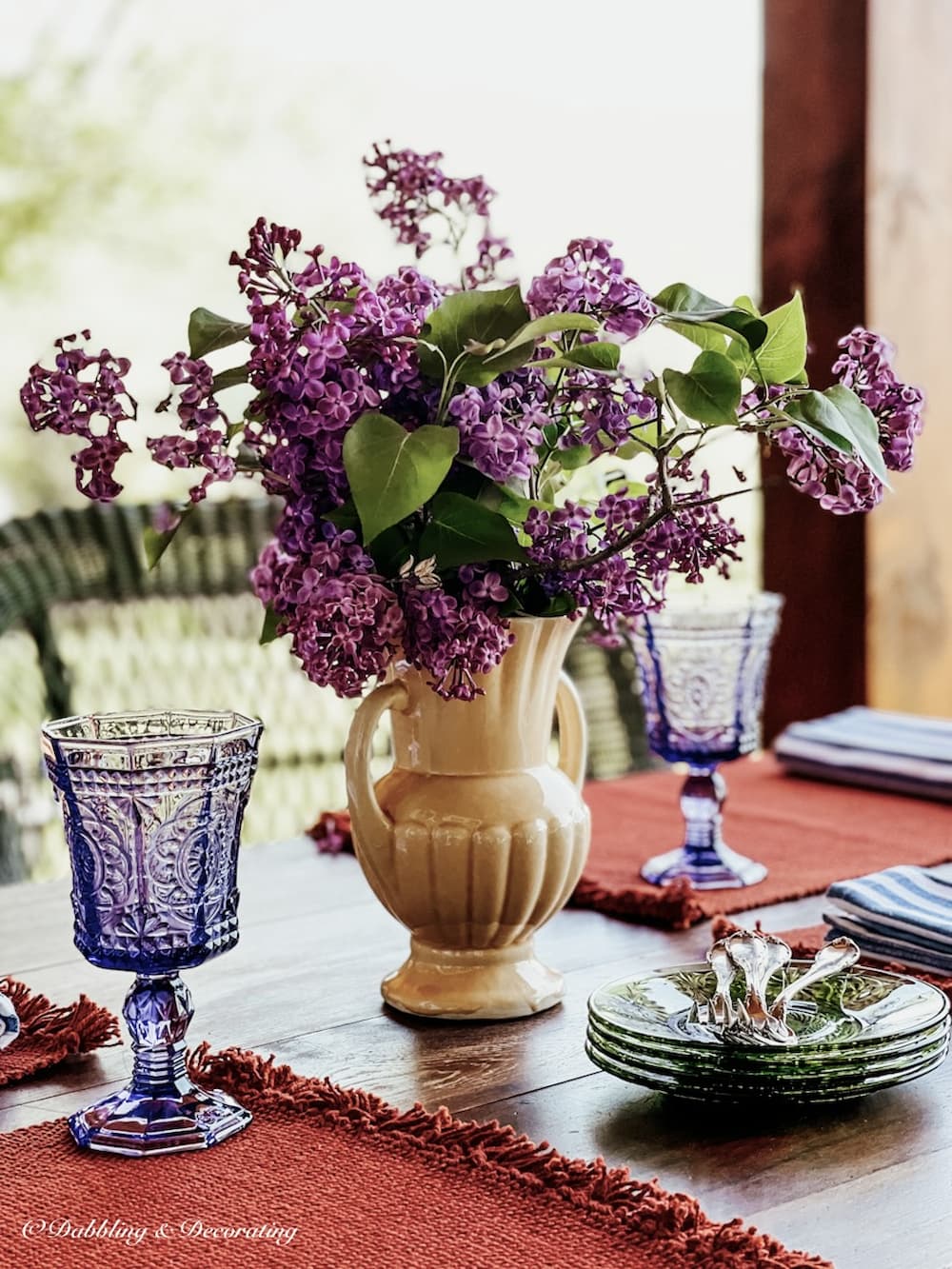 Lilac bouquet in vintage McCoy vase on outdoor table.