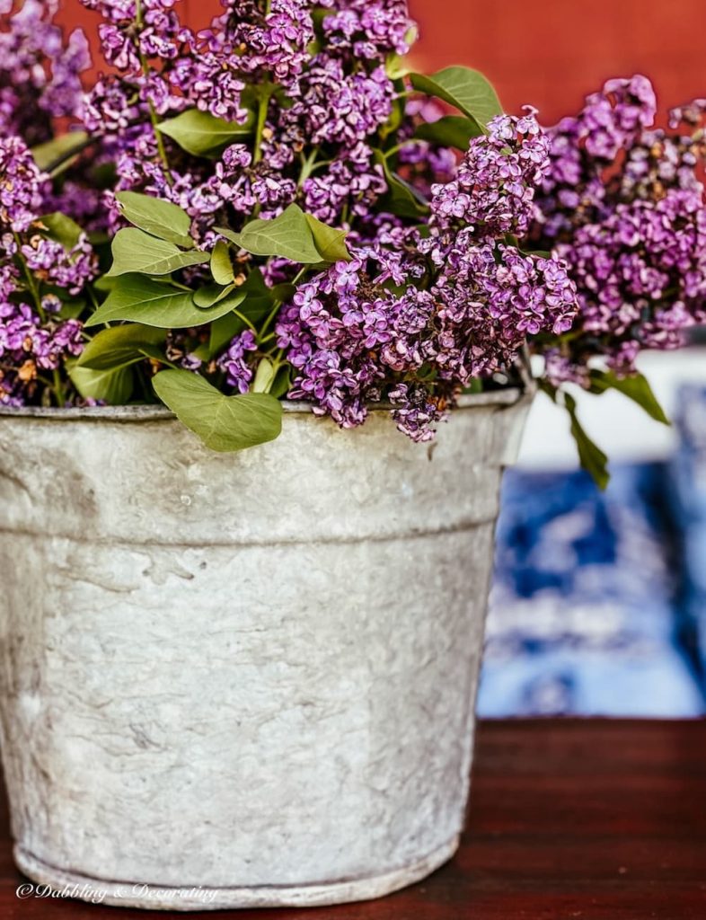 Galvanized Bucket Flower Arrangements with lilacs on porch table.
