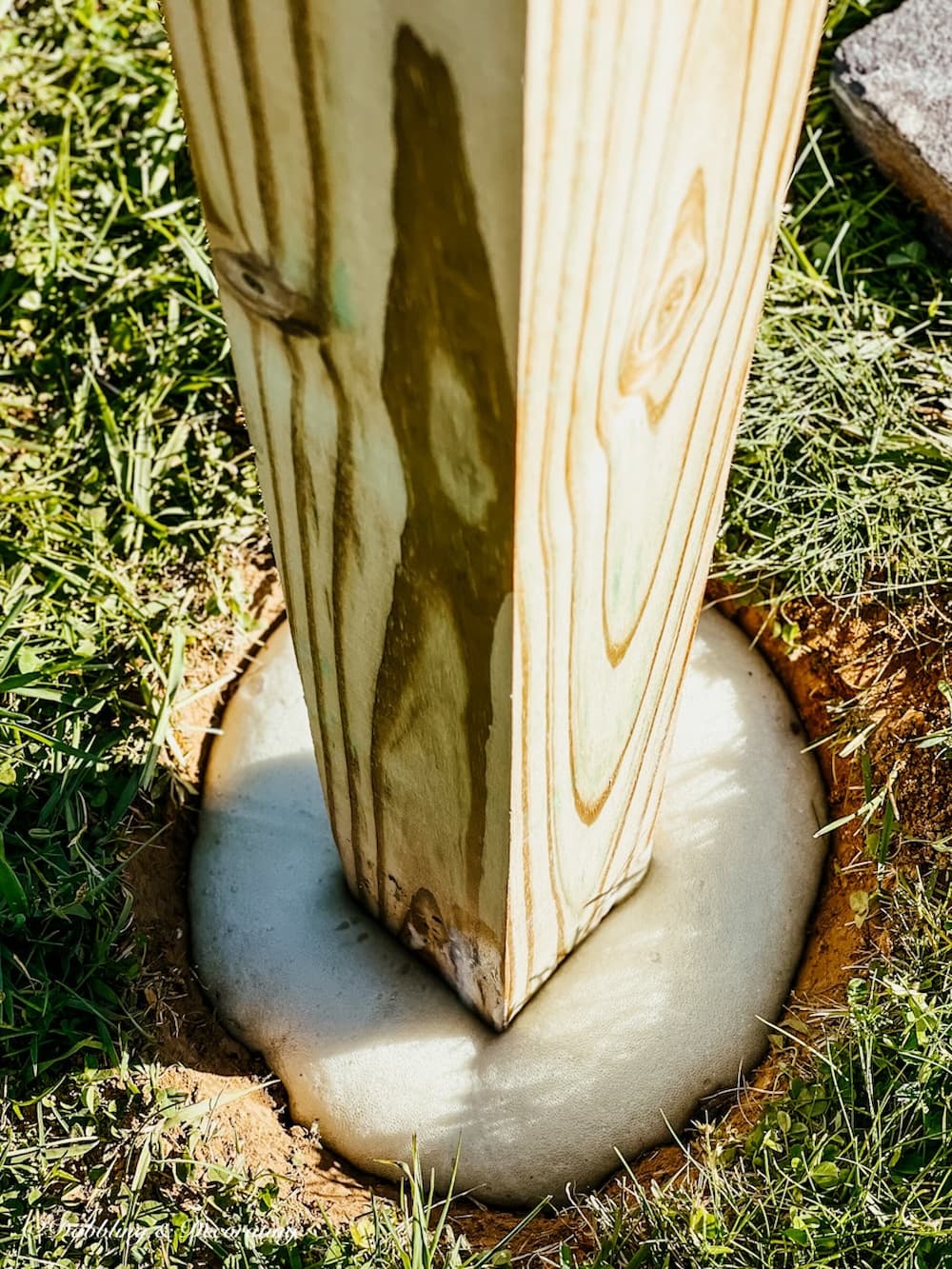 Amish birdhouse wooden post in cement hardening in ground.