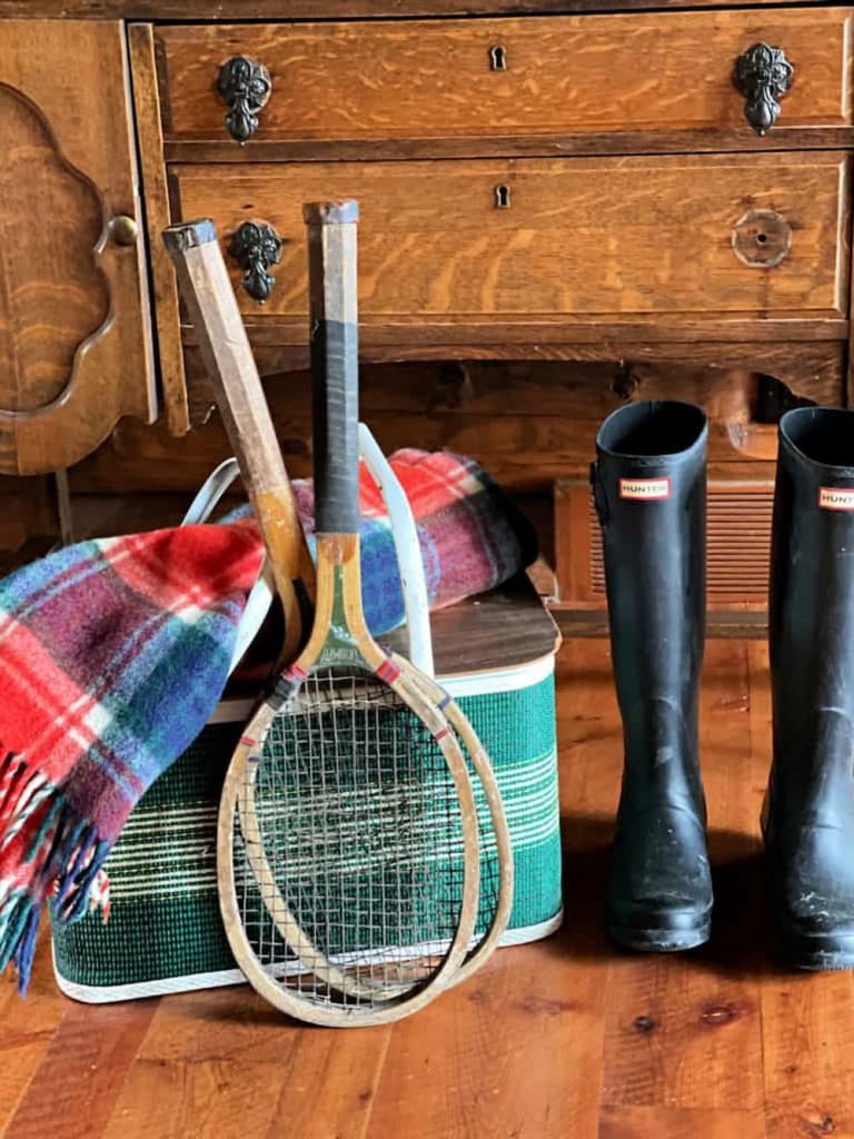 Vintage picnic basket in green with tennis racquets and boots.