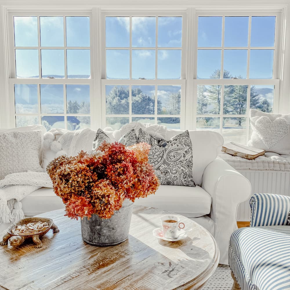 Galvanized Bucket Centerpiece with dried hydrangeas on coffee table in sunroom.