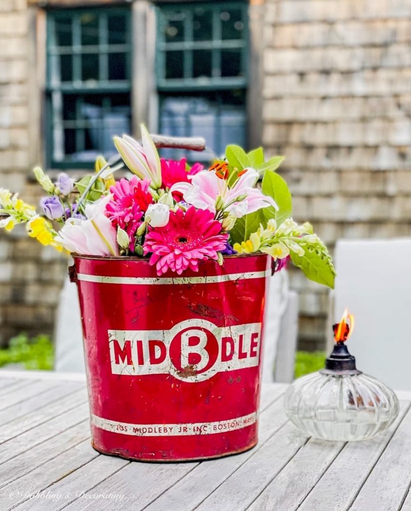 Red galvanized flower buckets with flowers.