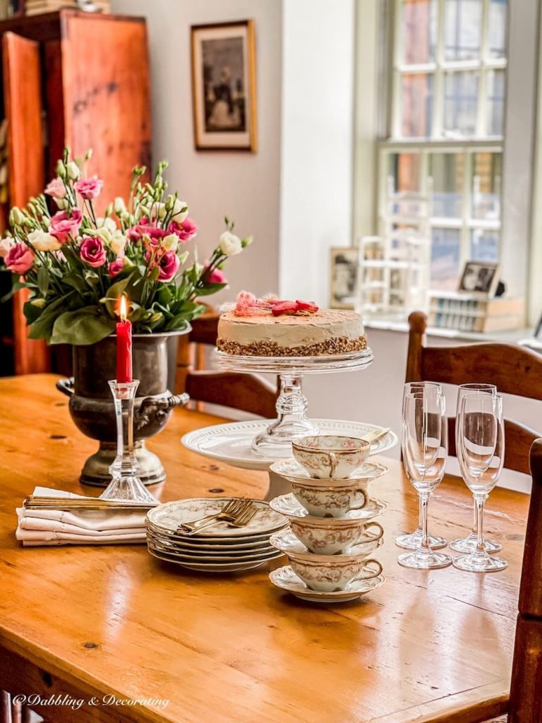 Table Ready Fakery Bakery on stacked cake plates on dessert set table with antique tea cups and champagne flutes.