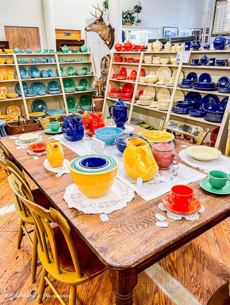 A large curated vintage booth at Cabot Mill Antiques in Brunswick, Maine filled with colorful vintage dishes.