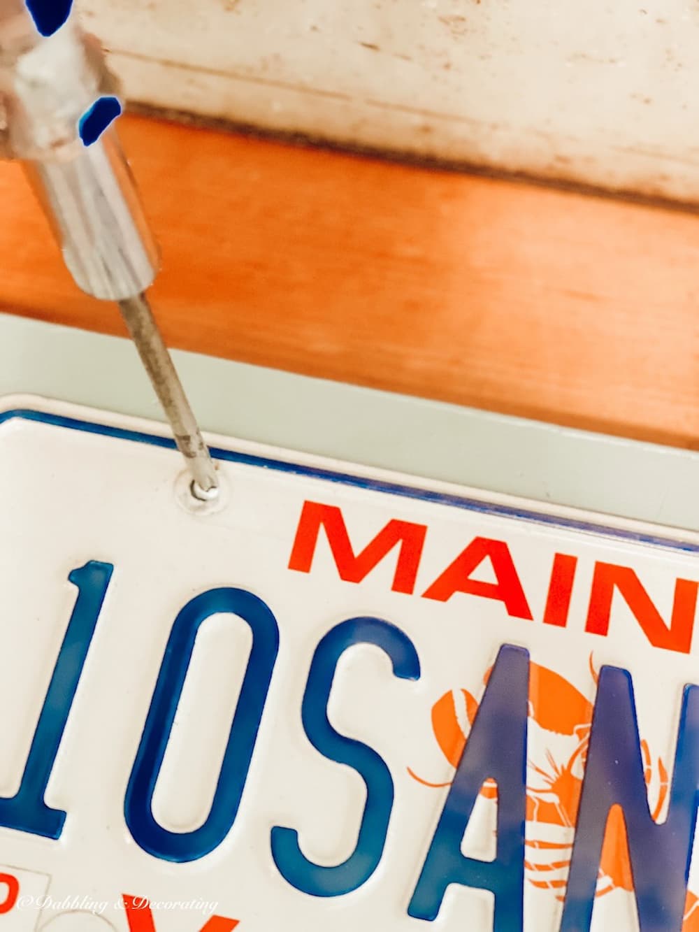 Screwing in a Maine Vanity License Plate to a Board.