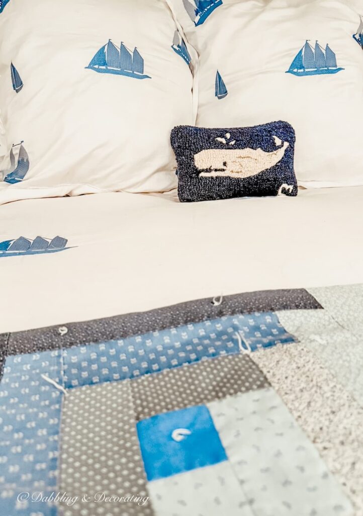 White and blue coastal sailboat bedding from Schweitzer Linen with a blue quilt and small whale pillow.