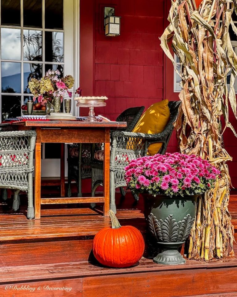 DIY plastic urn planter with purple mums and pumpkin on fall front porch.
