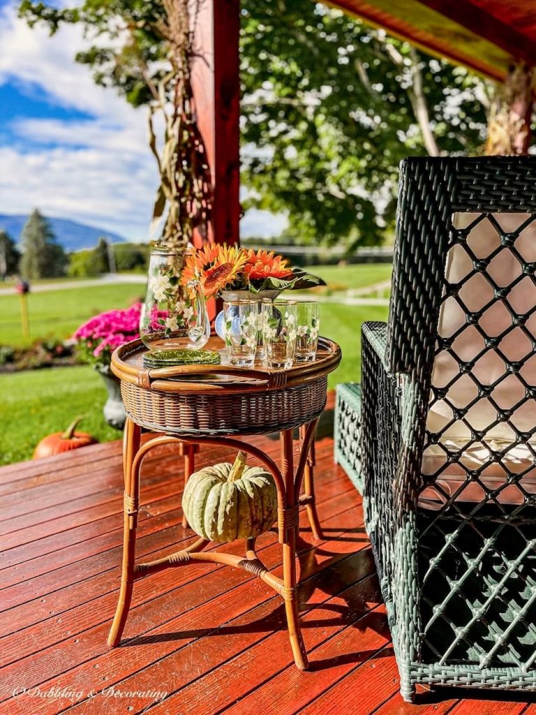 Porch furniture idea with all weather wicker furniture styled on a fall covered porch with pumpkins and mums in Vermont mountains.