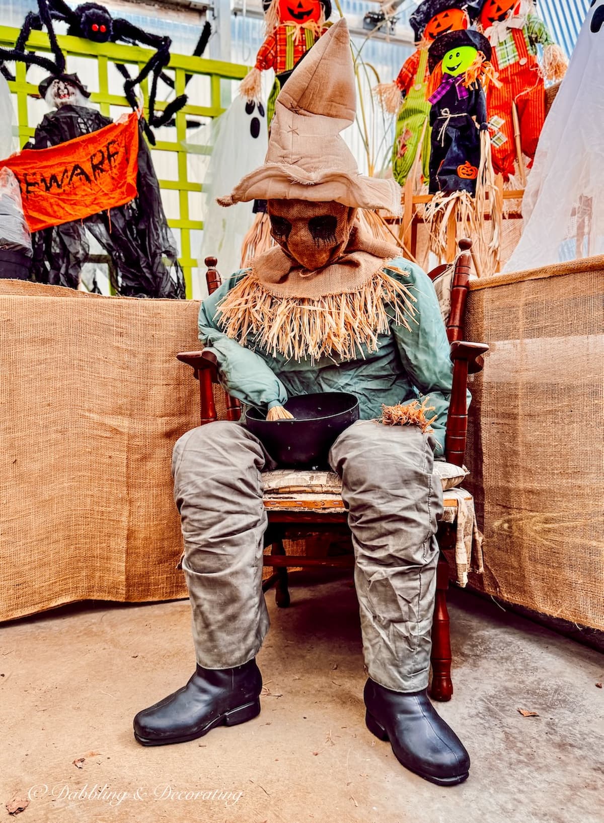 Funny scary scarecrow sitting in chair with hand in bowl.