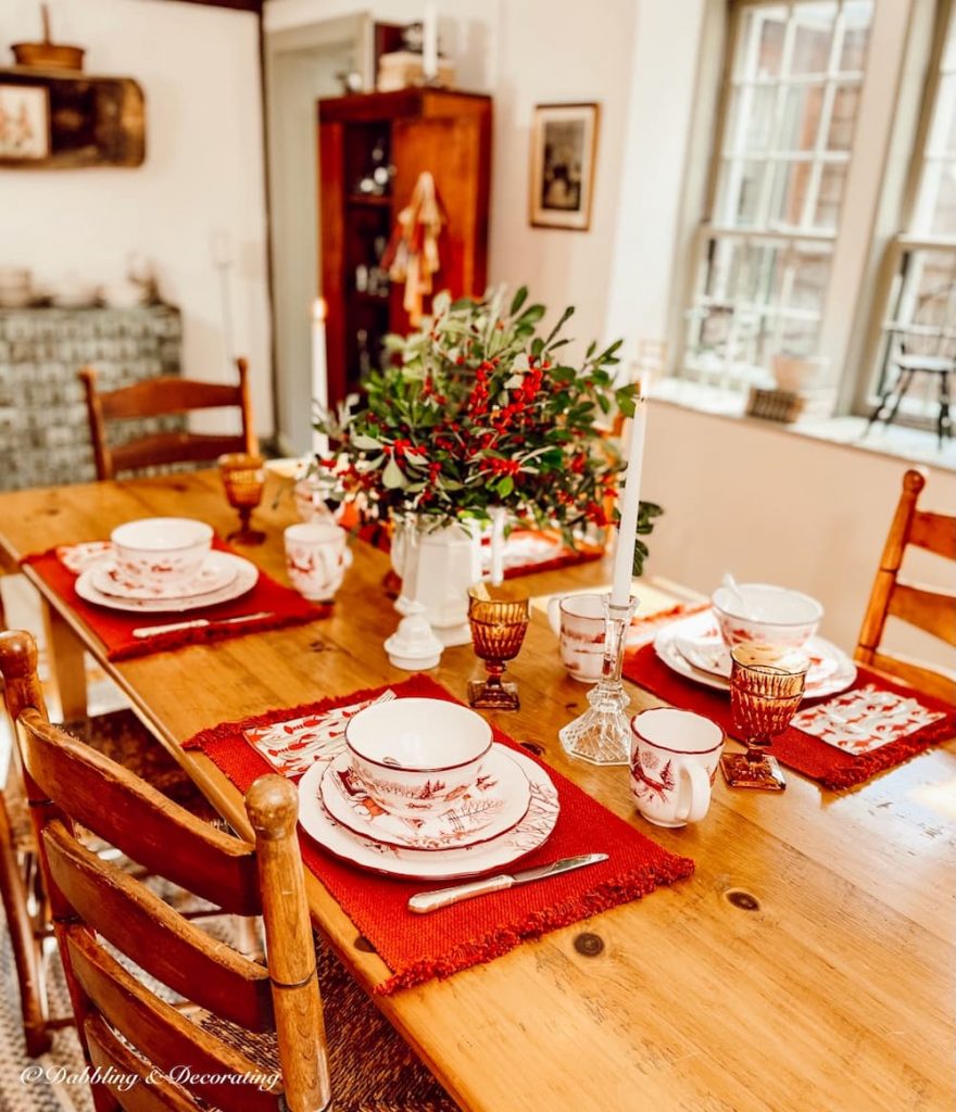 The Finest Winter Wonderland Dinnerware Set displayed on a wooden pine table with winterberry centerpiece.