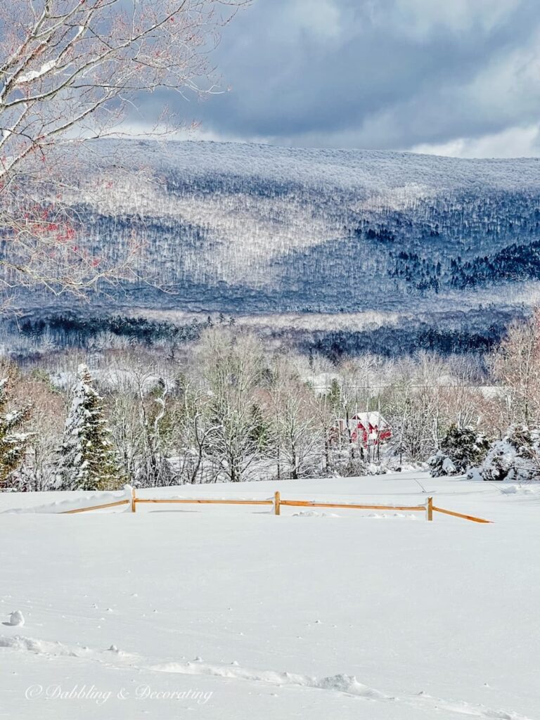 Snowy season with mountains and covered split rail fencing.