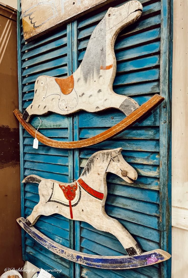 Antique Christmas decorations with blue shutters and wall hanging painted wooden horses.