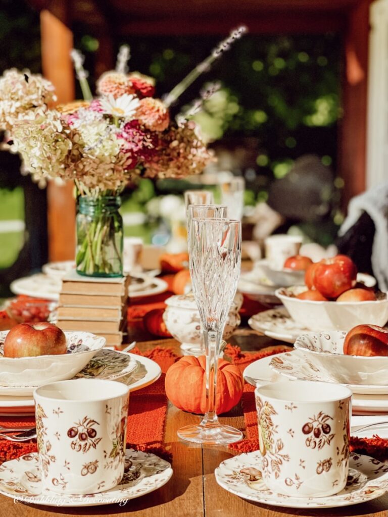 Vintage dinnerware and book collection on outdoor table.