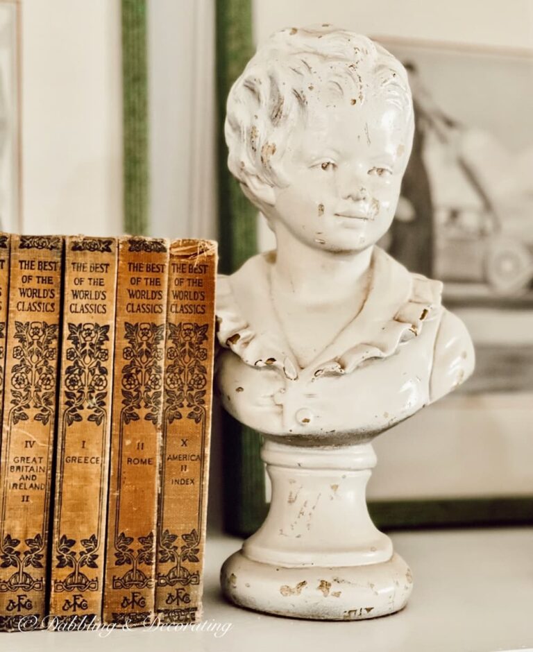 Vintage white bust with antique books displayed on bookshelf.