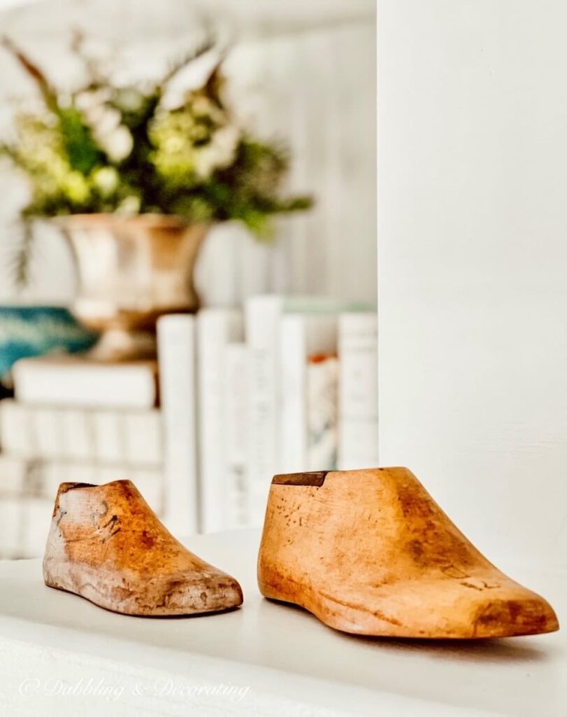 Two vintage wood cobbler shoe molds on white mantel.