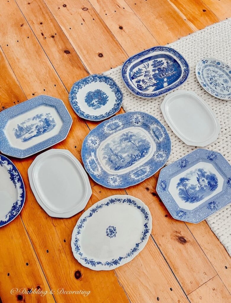 Vintage blue and white platter collection laid out on floor for wall design.