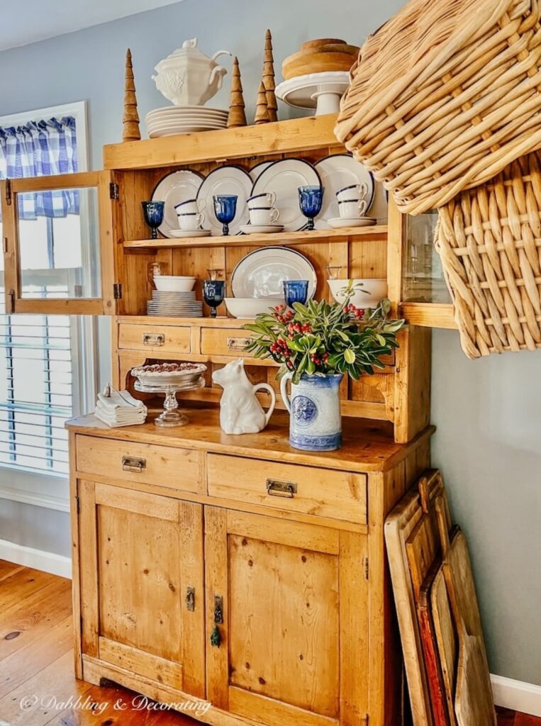 Wall baskets next to vintage china hutch cabinet.