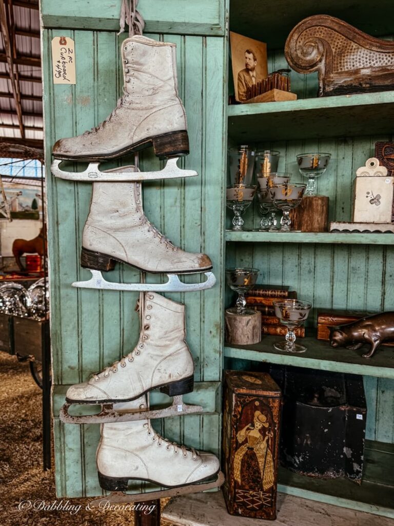 Aqua vintage hutch with white vintage ice skates hanging on the open door at Country Living Fair.