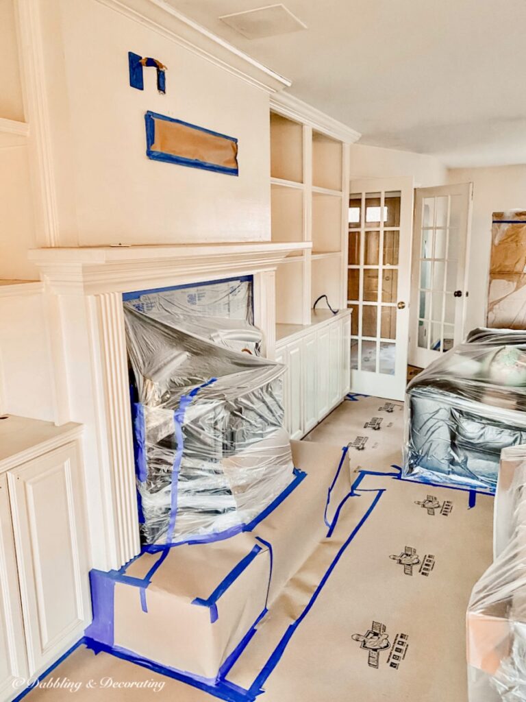 Painting preparations for Sherwin-Williams Stardew with plastic, floor coverings in open floor plan living room.