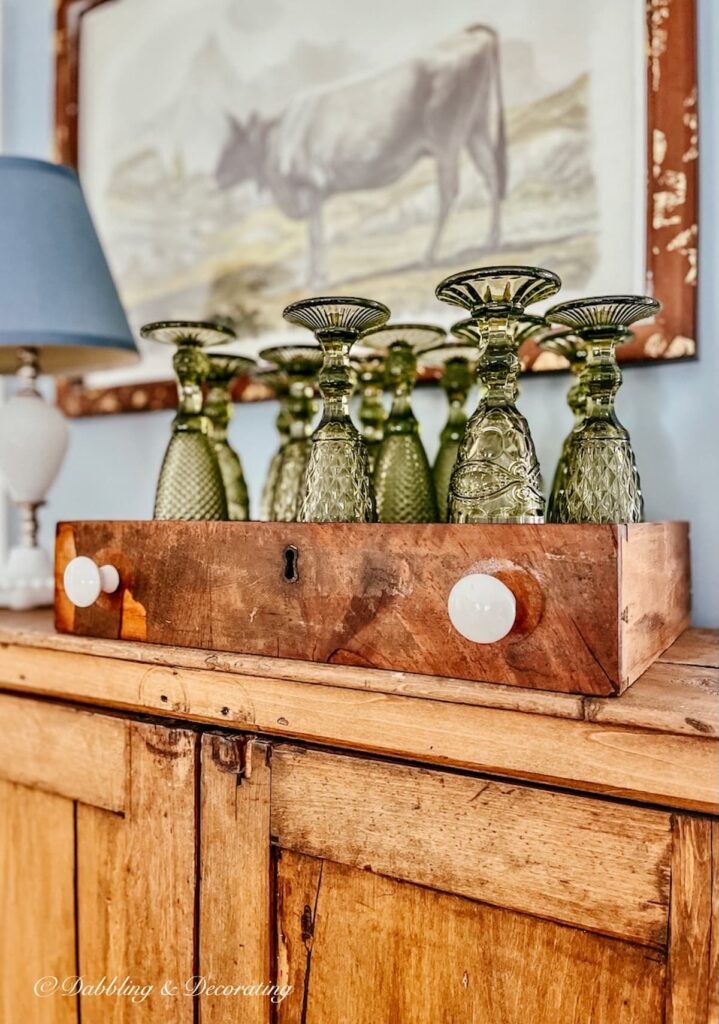 Green Glasses on Vintage Hutch next to Sherwin Williams Stardew painted wall.