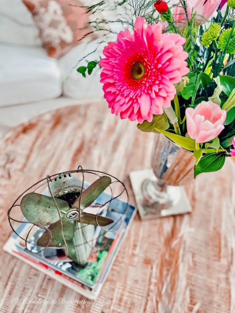 Vintage and eclectic accessories on coffee table, like fan and vase of flowers.