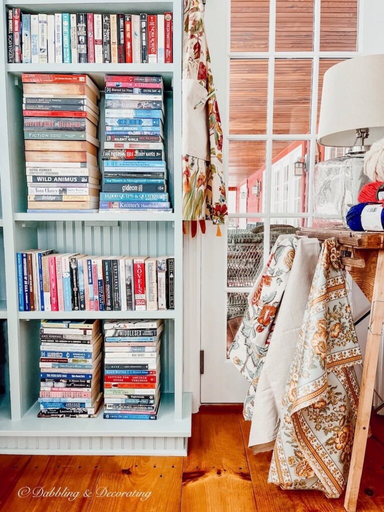 Built-in Bookshelves with stacked book next to a craft table in a sunroom craft room space at home.