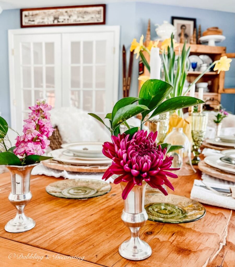 Spring Tablescape with Daffodils and small silver bud vases with pink accent flowers.