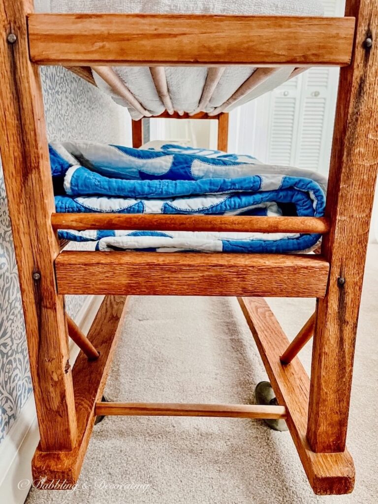 vintage cobbler shoe stand with blue and white quilt on bottom shelf.