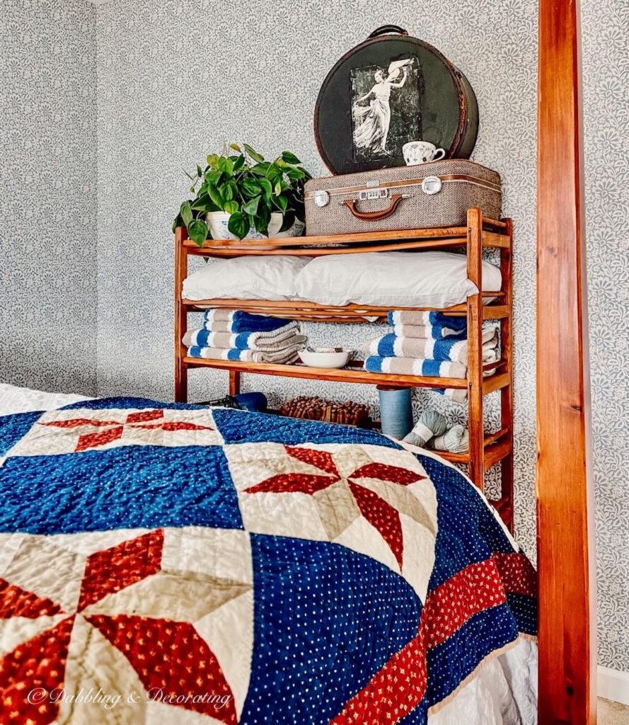 Vintage cobbler shoe stand styled in guest bedroom with four poster bed and antique quilt.