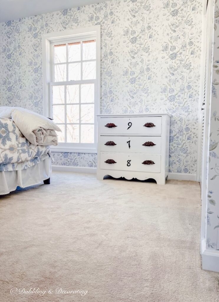 painted white dresser refashioned with wrought iron house numbers in wallpapered bedroom.