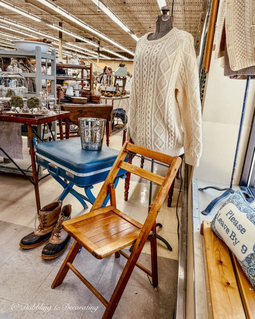 Van Claus Designs vintage booth design with suitcase, chair and mannequin with sweater.