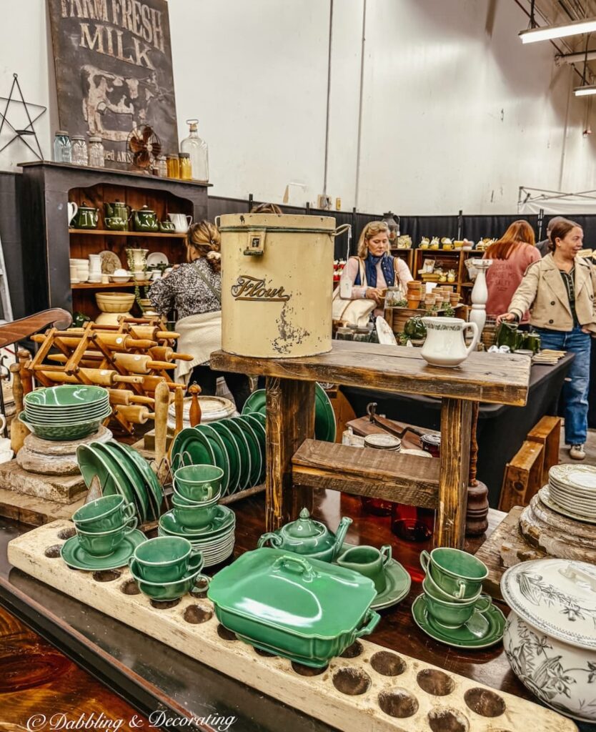Vintage styled booth at Vintage Bazaar New England with green dishware, vintage tins, crates and more.