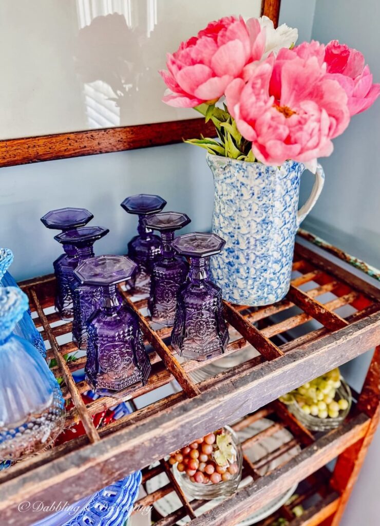 Peonies and purple glassware on antique cobblers rack