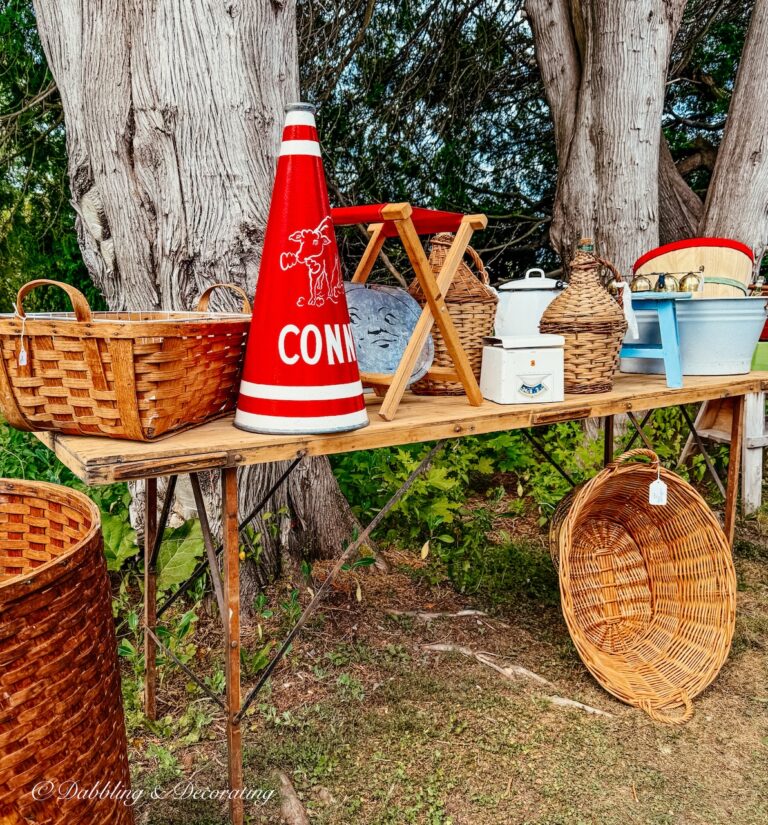 Barn sale table with vintage decor accessories including red bullhorn and baskets outdoors.