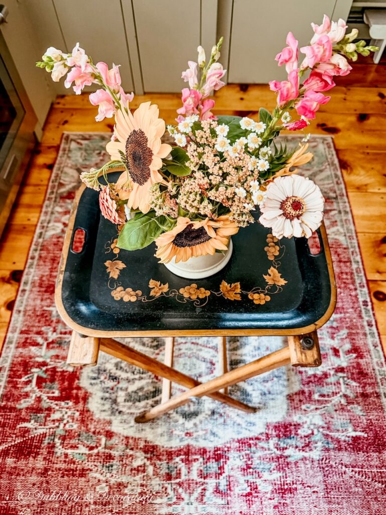 Antique waitress tray station with black antique tray and bouquet of summer flowers in middle of vintage kitchen.