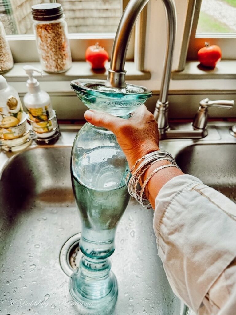 Nautical glass vase filling with water in sink.