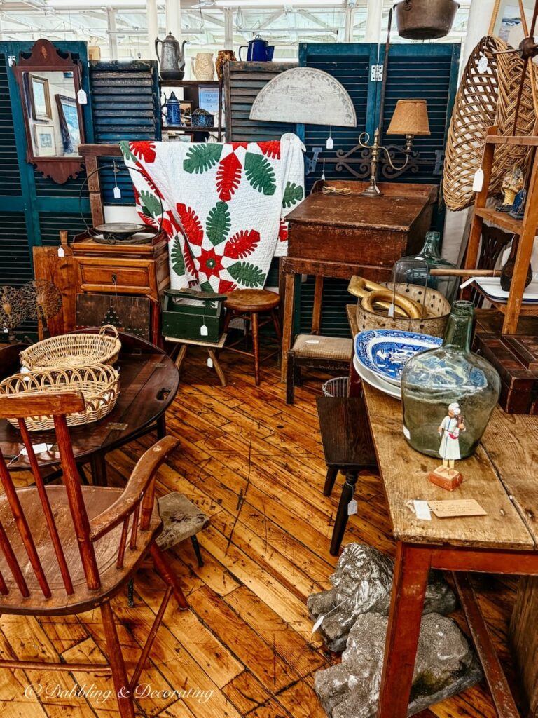 Inside an antique booth at Cabot Mill Antiques with green and red quilt displayed.