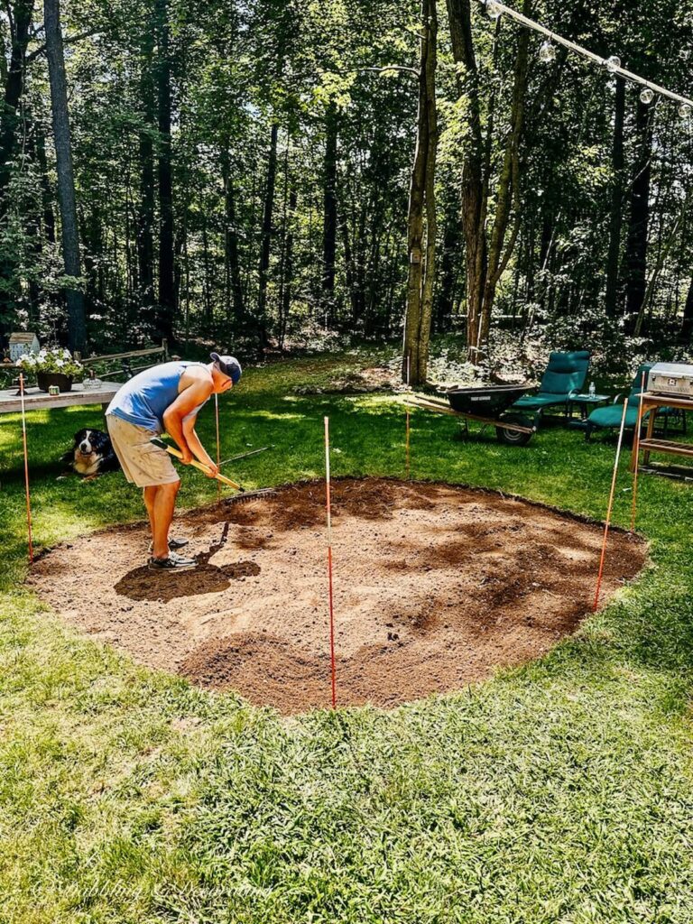 Man Raking a dirt building a small pea gravel patio.