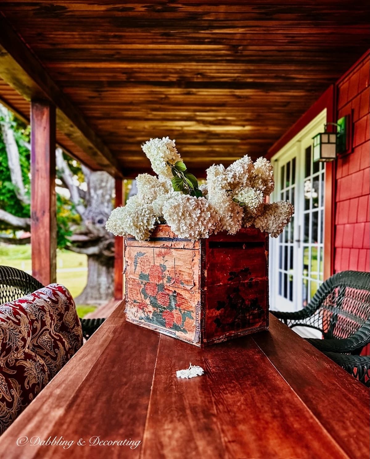 Vintage hydrangeas arrangement in crate on Vermont home's porch. The Unexpected Red Theory in action. Front porch flower pots ideas.